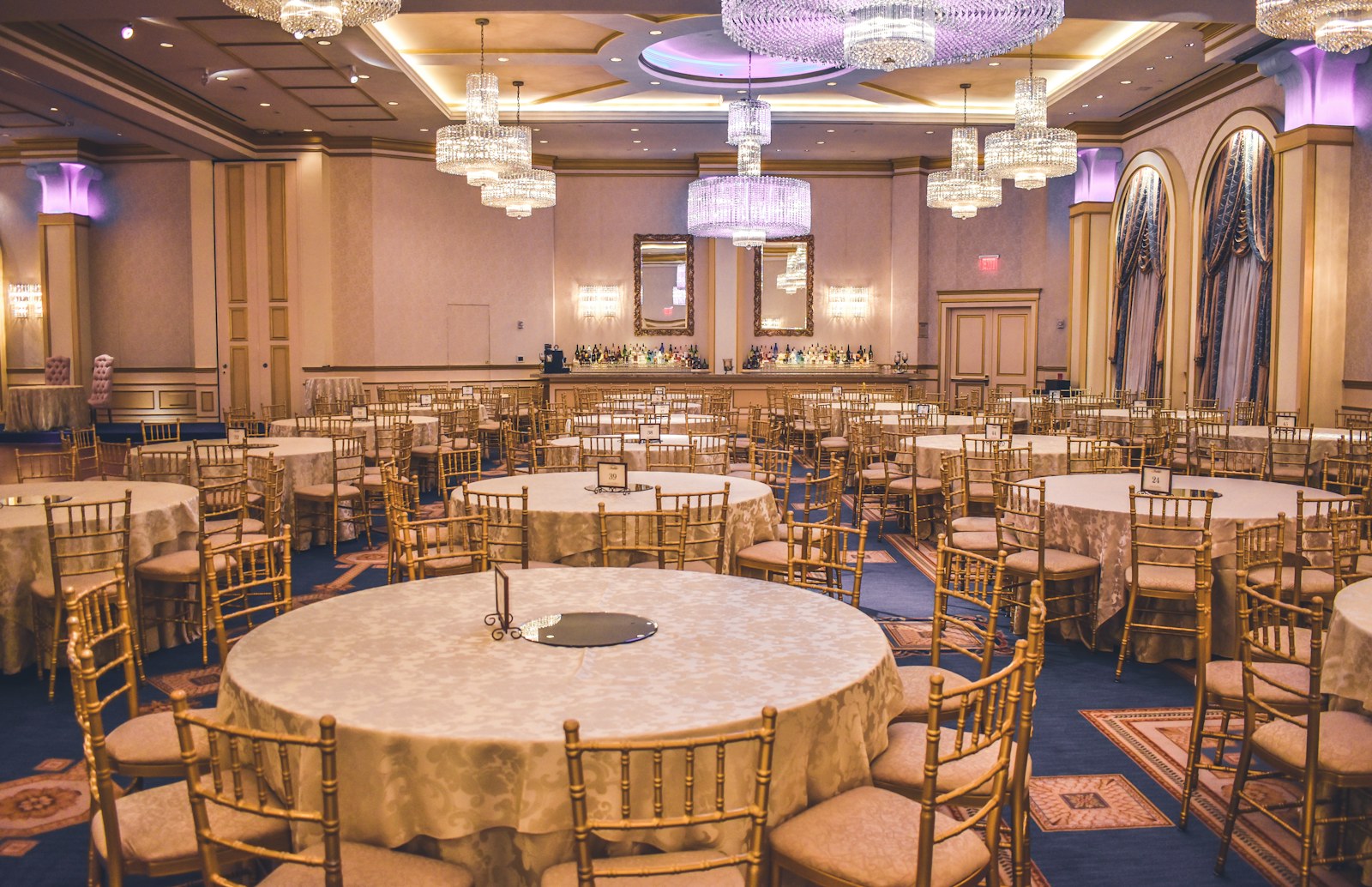 A ballroom set for an event with round tables and chandeliers.