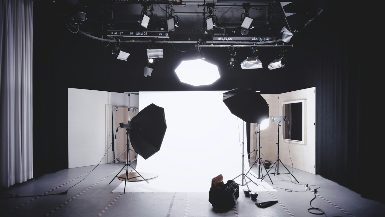 A dark photography studio with a white cyclorama, softboxes and overhead lights.